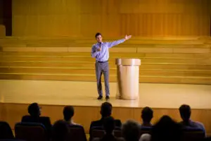 Keynote speaker presenting on stage at a UK tech conference in London.